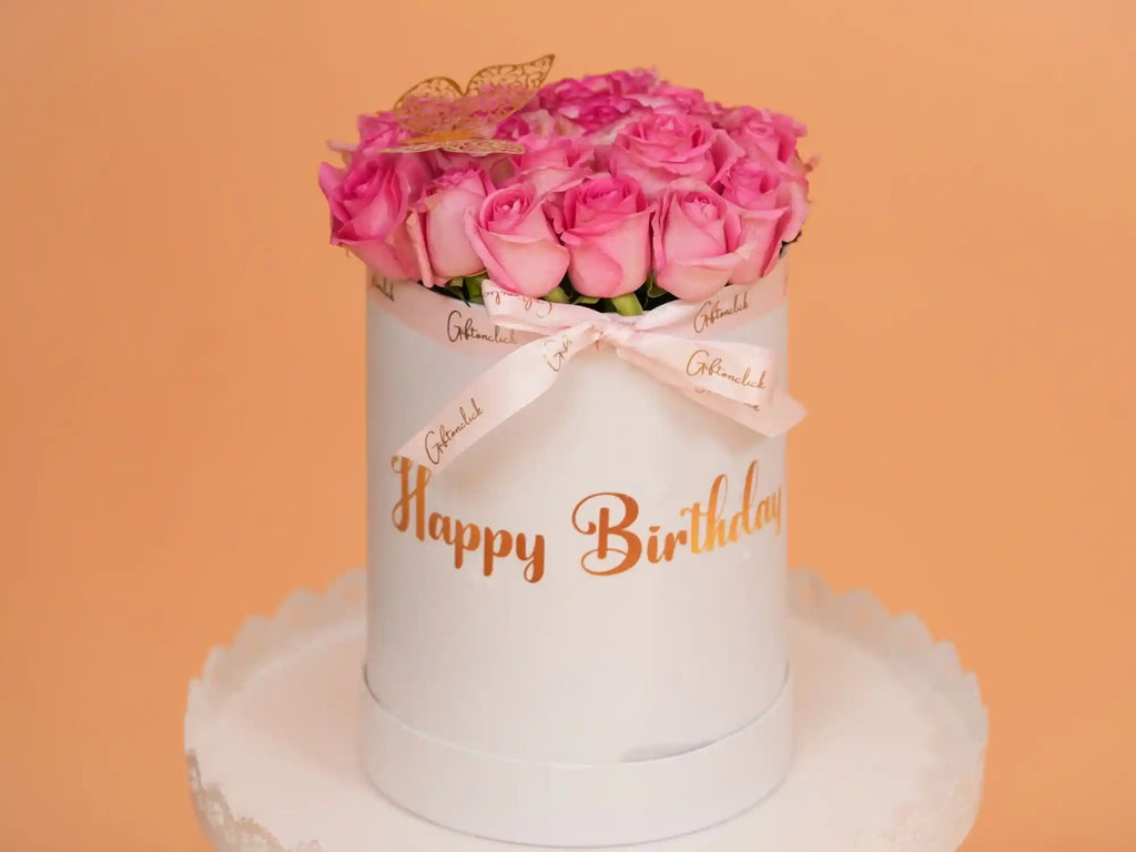White cylindrical box with pink roses and 'Happy Birthday' text on an orange background