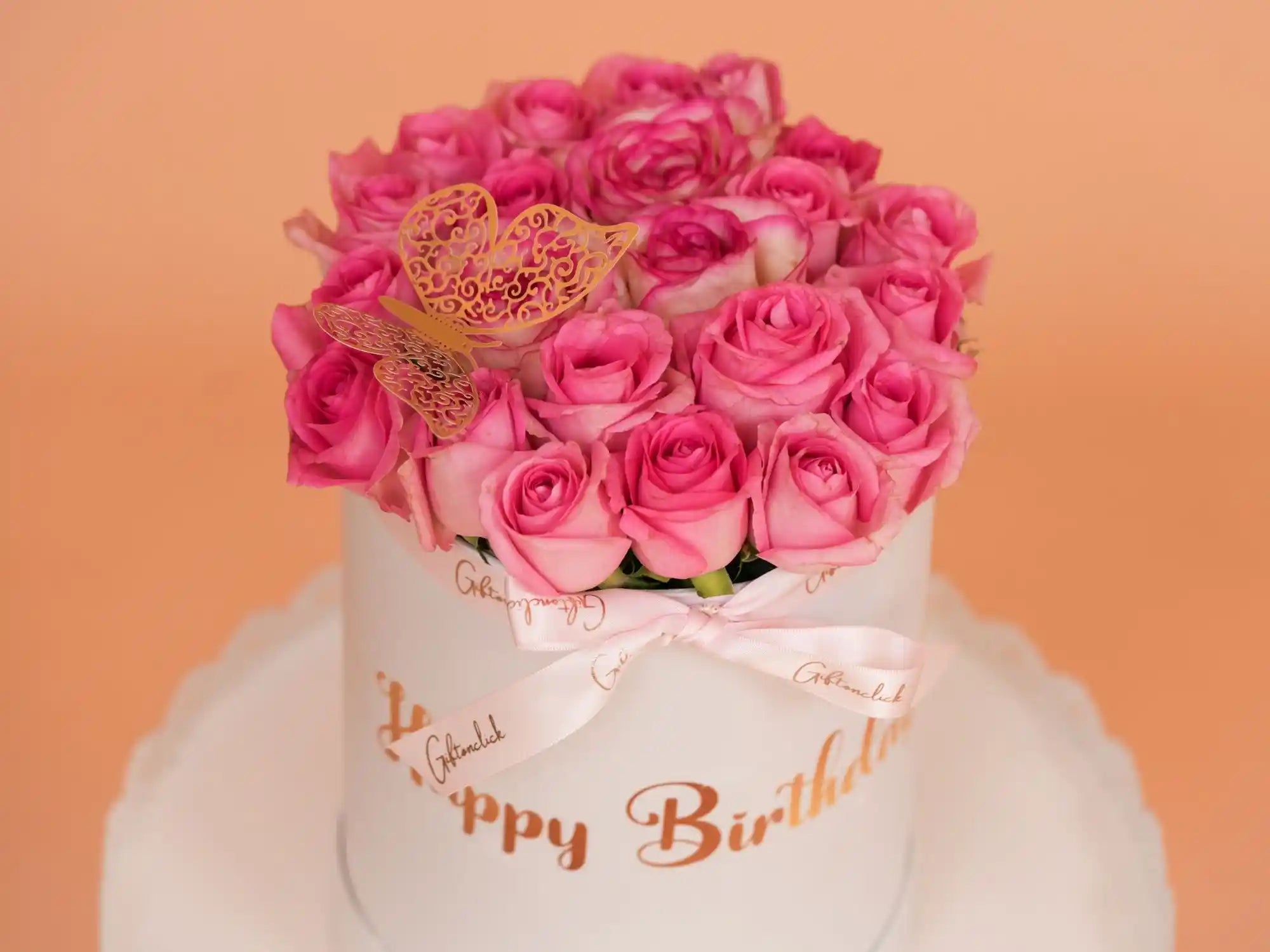Bouquet of pink roses in a white box with 'Happy Birthday' text on an orange background
