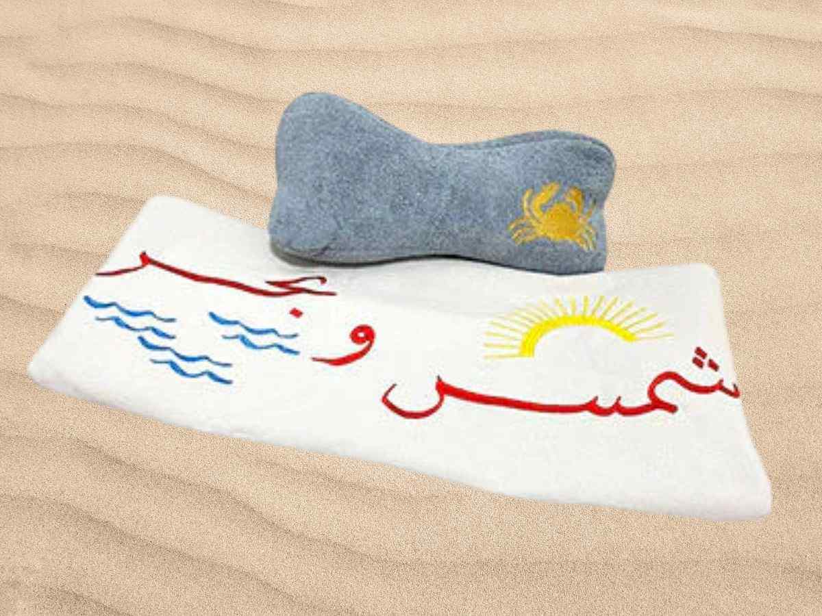 beach set of Gray pillow and white towel with Arabic text and graphics 