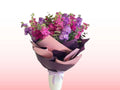 Bouquet of flowers wrapped in purple paper on a gradient pink and white background