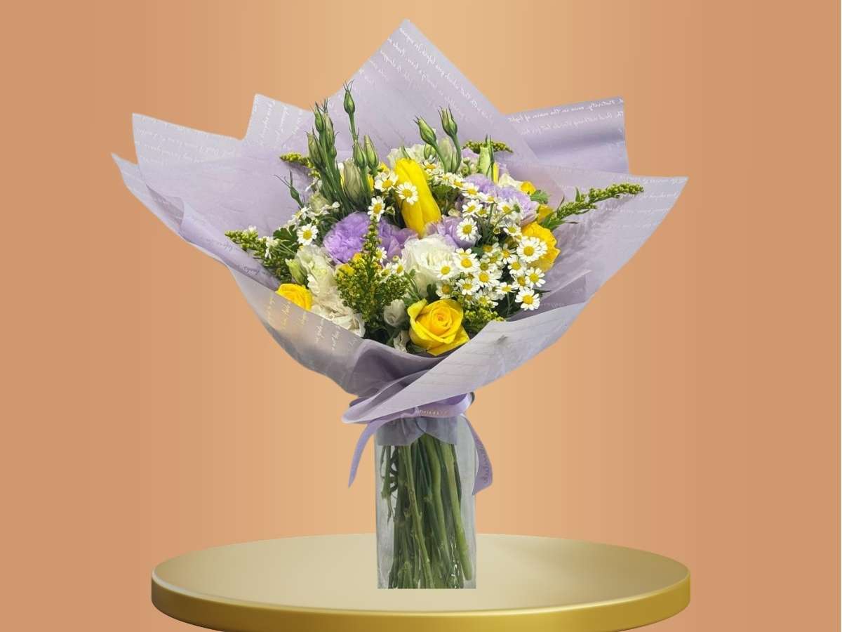 Bouquet of flowers wrapped in purple paper on a gold stand with a beige background