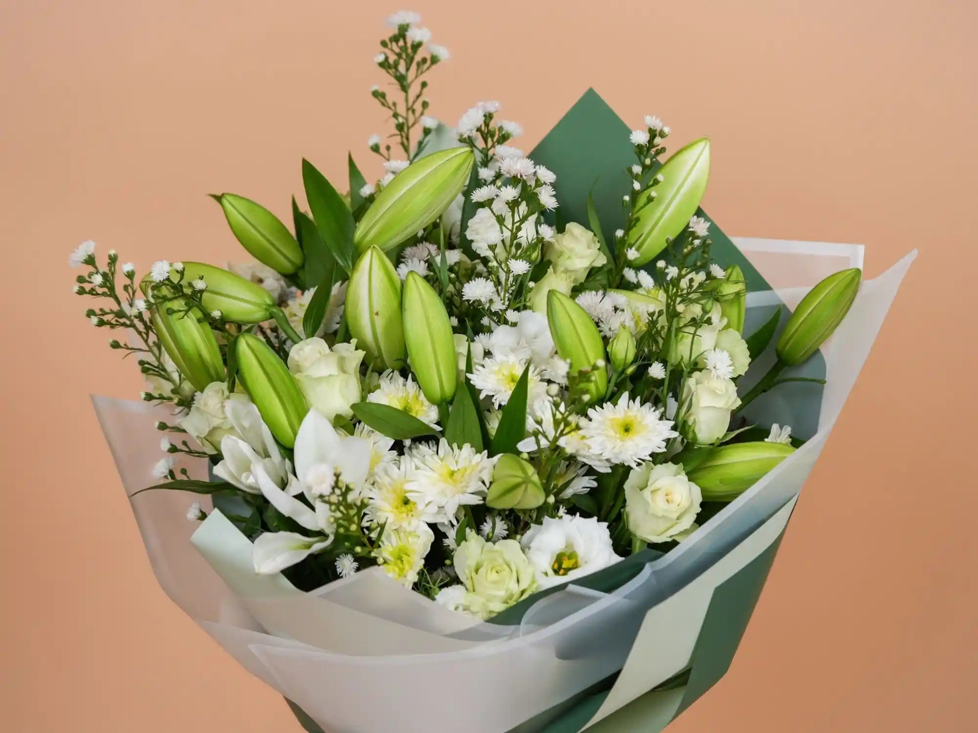 Bouquet of green and white flowers wrapped in paper against a beige background