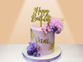 purple cake with birthday topper and flowers