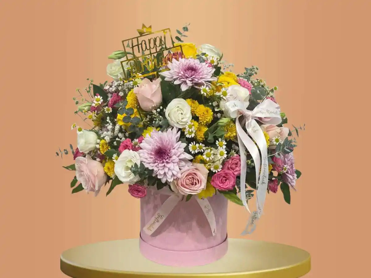 box filled with mixed flowers and happy birthday topper