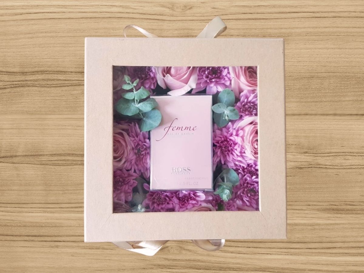 giftbox with feminine perfume surrounded by fresh flowers