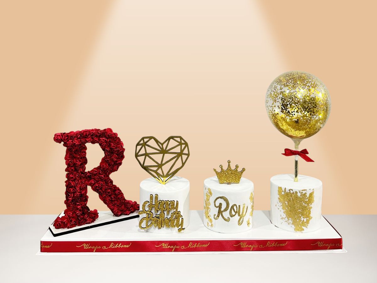 three cakes on board with flower letter and balloon